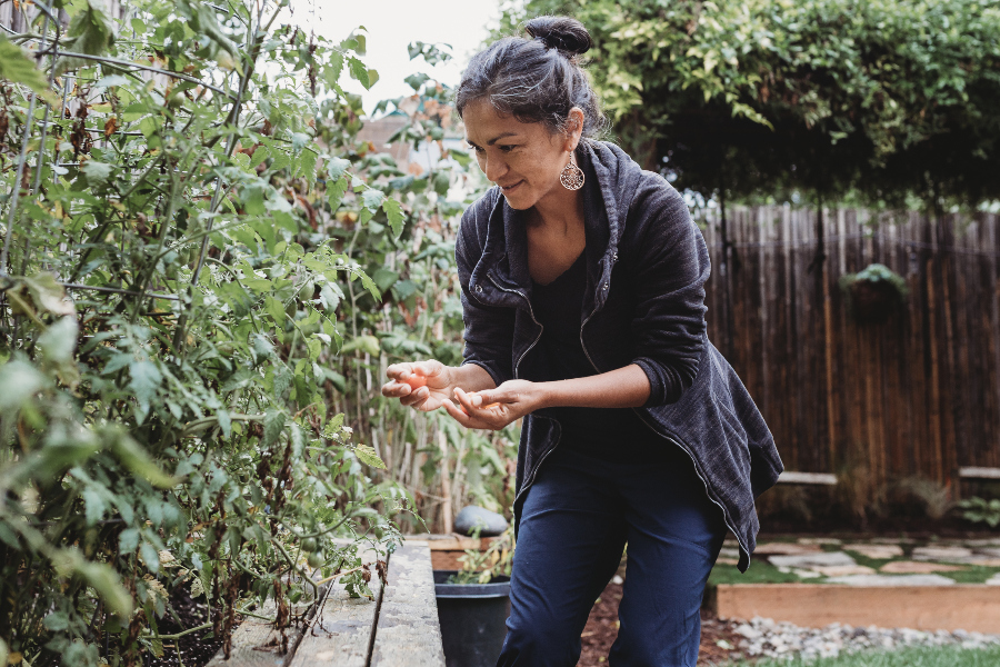 Woman picks vegetables from her garden.