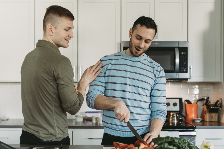Two men prep food at a kitchen island.