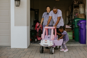 A family plays with a toy car in front of their new development southern home.