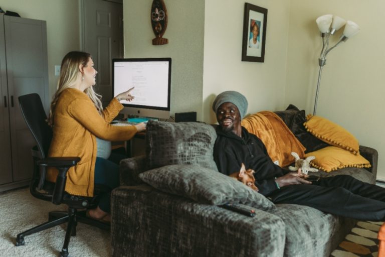 Couple hangs out in their living room and looks things up on their computer.